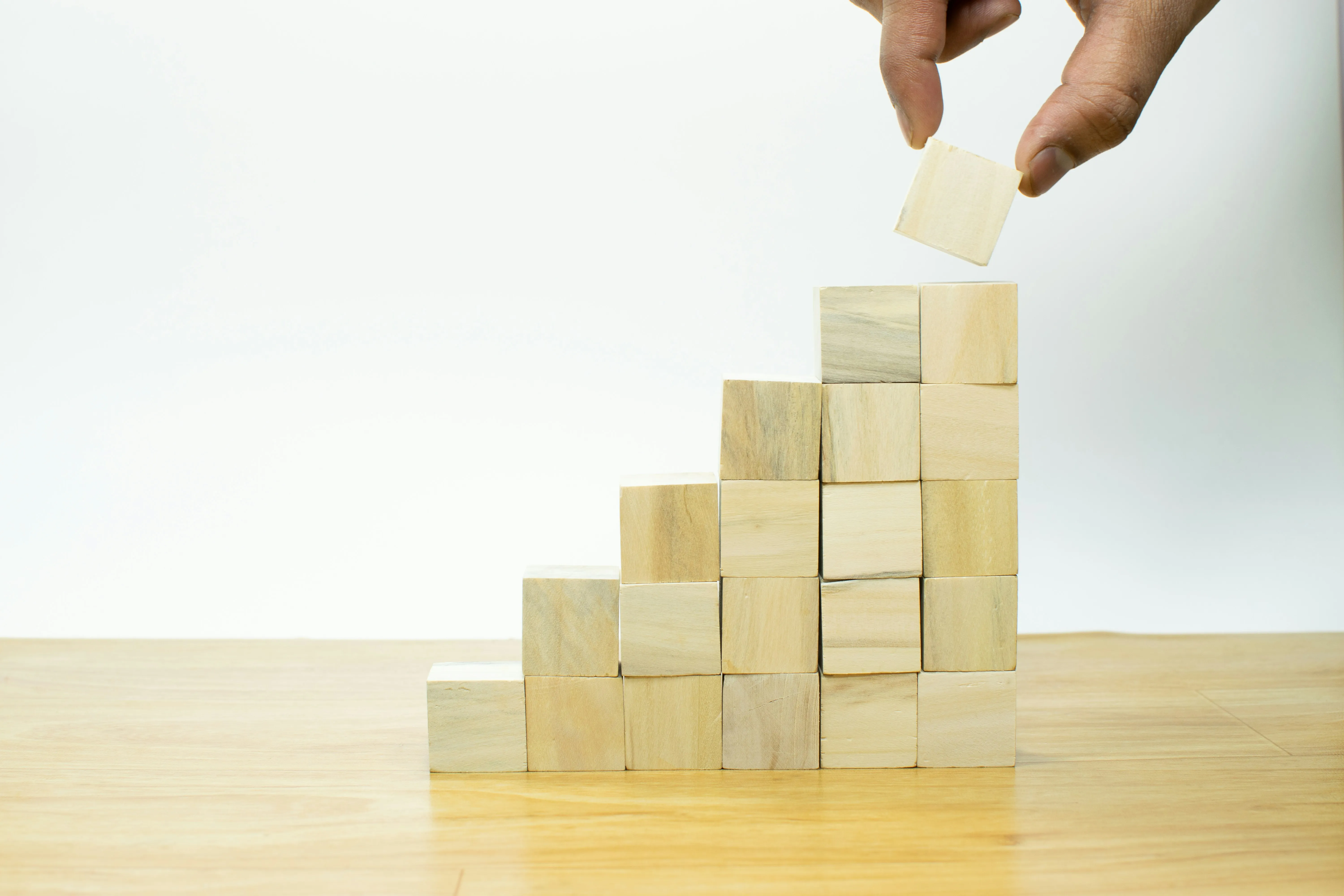 Hand stacking wooden blocks, symbolising self-management as a core leadership issue